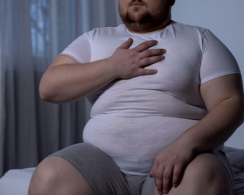 overweight man holding chest