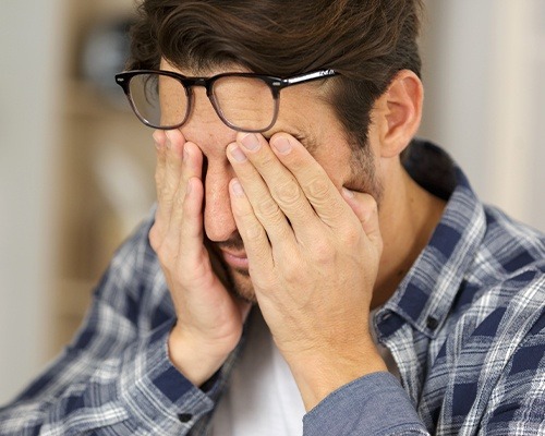 man rubbing eyes under glasses