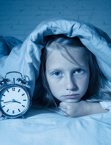 kid under cover with clock