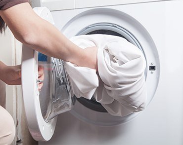 woman putting sheets in washer