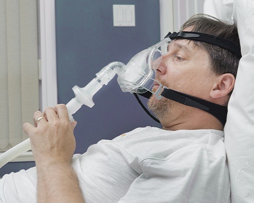 man holding cpap machine to face