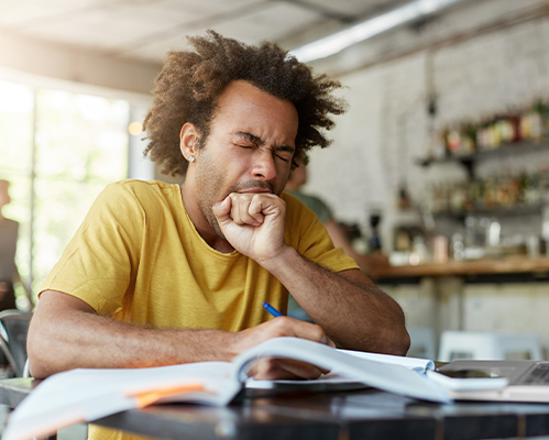 man yawning doing school work