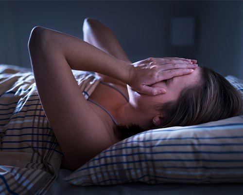 woman covering face in bed