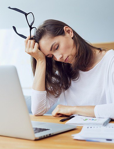 woman closing eyes in front of laptop