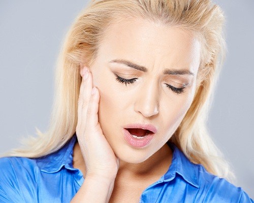 blonde woman holding jaw