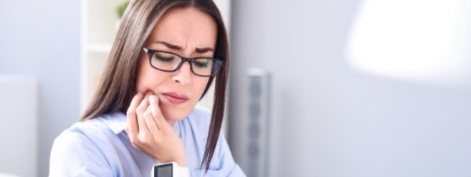 woman holding jaw in pain