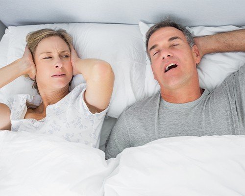 man snoring and woman covering ears