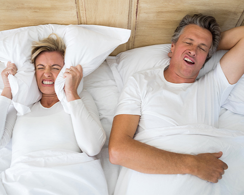 woman covering ears with pillow