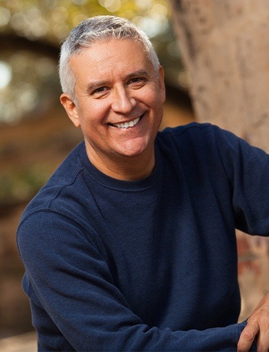 man smiling outside by tree