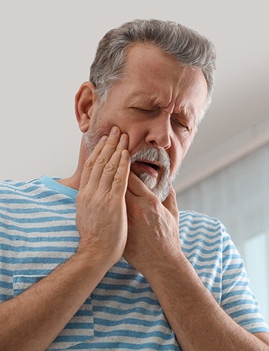 man holding jaw and cheek