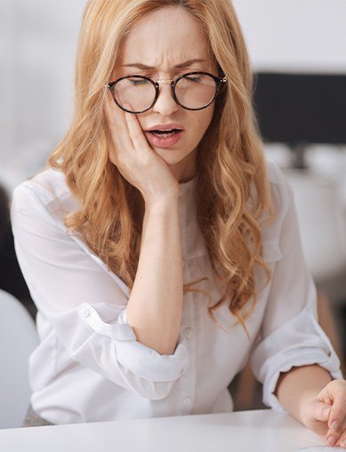 woman with glasses holding onto jaw