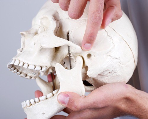 finger pointing to TMJ point on skull