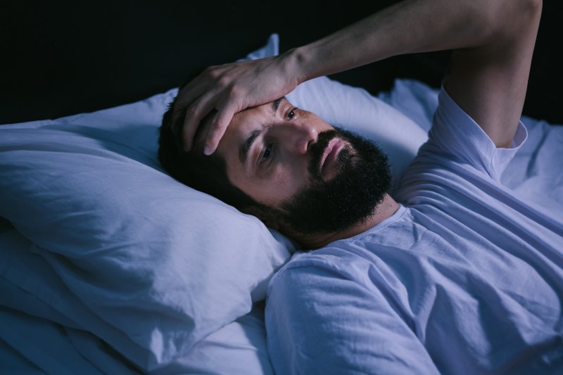 Bearded man being kept up by his sleep apnea