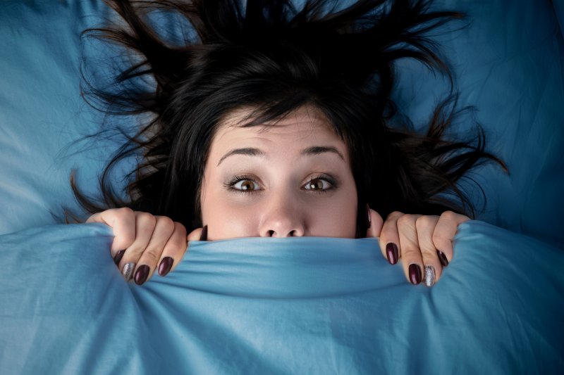 Woman under covers having woken up from nightmare