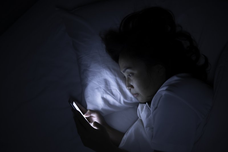 Woman playing on her cell phone at night in bed