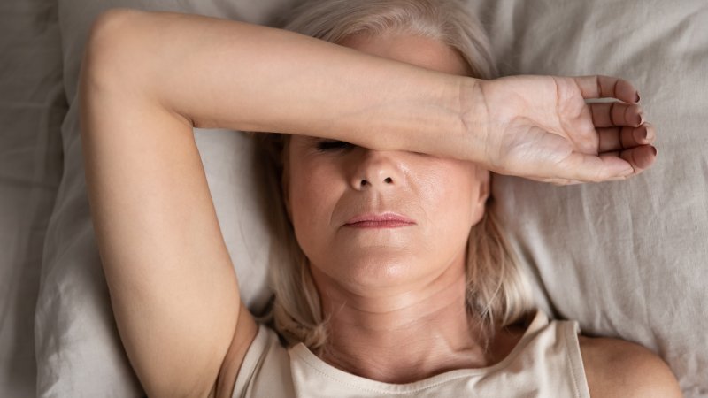 Woman awake in bed with arm over eyes