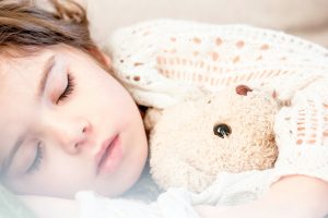 Young girl sleeping and holding a teddy bear
