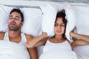 Woman in bed holding pillow over her ears