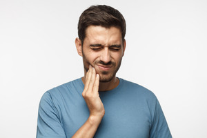 Man with TMJ disorder rubbing jaw in pain