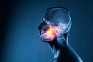 Illustration of human skull with TMJ highlighted in red